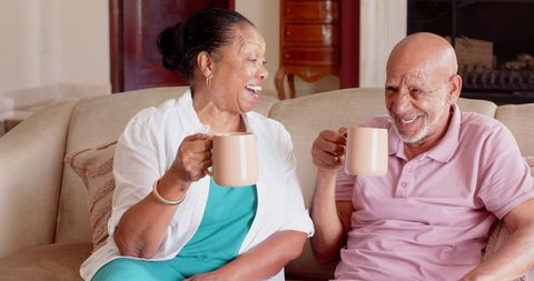 Joyful Senior Couple Sharing Moment with Ceramic Mugs at Home