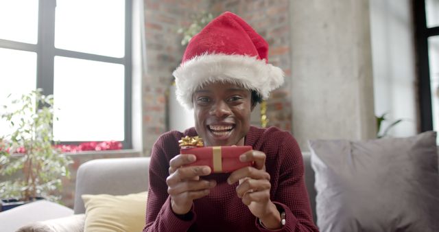 Happy Person Wearing Santa Hat Holding Gift During Christmas Celebration - Download Free Stock Images Pikwizard.com