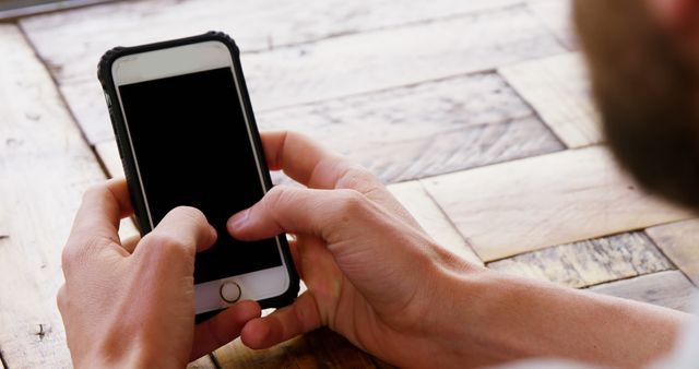 Male hands holding and texting on smartphone, focusing on the device and interaction. Ideal for illustrating modern technology usage, online communication, digital lifestyle, mobile apps, and connectivity.