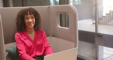 African american woman working on laptop in modern office booth
