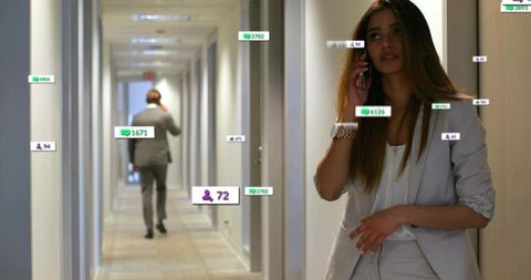 Female executive talking on phone in office corridor with social engagement overlays