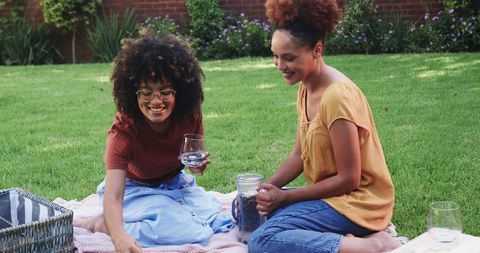 African american friends enjoying backyard picnic on blanket with pitcher and glasses