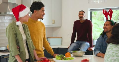 Friends enjoying holiday cooking in cheerful kitchen gathering