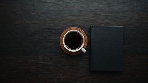 Coffee on Dark Wooden Table with Closed Book and Coaster