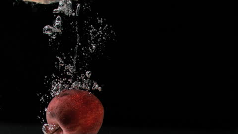 Red Apple Sinks Dramatically into Clear Water with Bubbles Rising