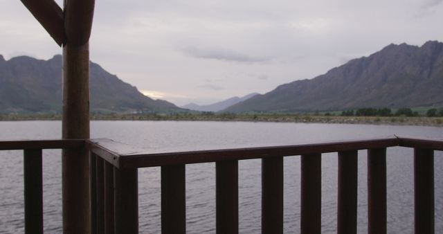 Serene Lakeside View from Wooden Balcony House, Mountains in Background - Download Free Stock Images Pikwizard.com