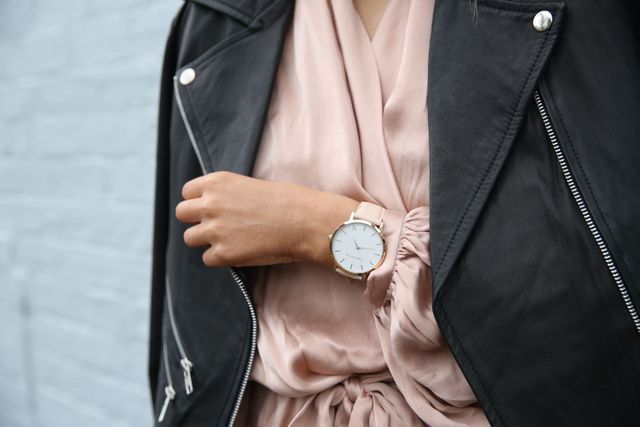 Fashion-forward woman showcasing casual yet elegant style with leather jacket and wristwatch. This image is ideal for use in fashion editorials, lifestyle blogs, watch advertisements, or online boutiques. Perfect for illustrating modern street style and luxury accessories in a contemporary setting.