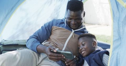 Father and son bonding inside tent on camping trip