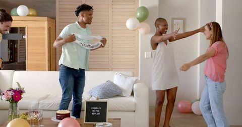 Friends Celebrating New Job with Balloons and Cake in Living Room
