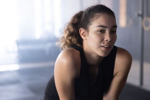 Determined young athlete resting between sets in industrial gym with hanging rings