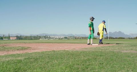 Senior Baseball Players Standing on Base in Sunny Outfield with Mountain Vista