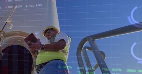 Man with Tablet against Wind Turbine and Financial Graphs