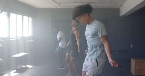 Diverse group of men focused on jump rope workout in gym