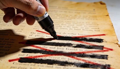 Hand Applying Black Marker Redaction on Vintage Book Page with Red X Marks