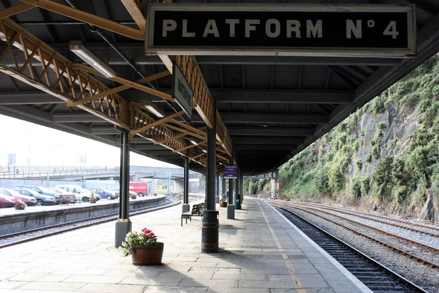 Empty railway platform at a train station showing tracks and an empty waiting area. Suitable for illustrating themes like travel, transportation, urban life, and architectural structures.