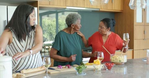 Multigenerational african american women cooking together sharing wine and conversation
