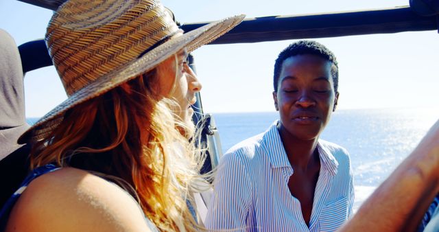 Two friends enjoying a road trip along a beautiful coastal drive, riding in a convertible car with clear blue sky and ocean in the background. The image displays friendship, travel, and adventure, capturing the essence of summer exploration. Useful for promoting travel agencies, road trip experiences, vacation packages, or lifestyle products.