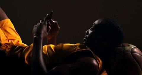 Afro-american basketball player texting at rest
