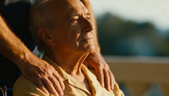 Sunlit senior man gazing upward while caregiver hands provide gentle support on balcony