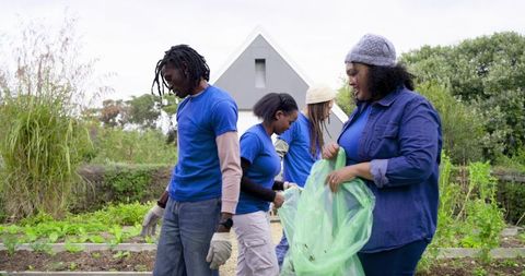 Multiracial Volunteers Tending Community Garden Raised Beds Wearing Blue Shirts and Gloves