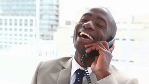 Businessman Joyfully Talking on Phone in Bright Office Setting