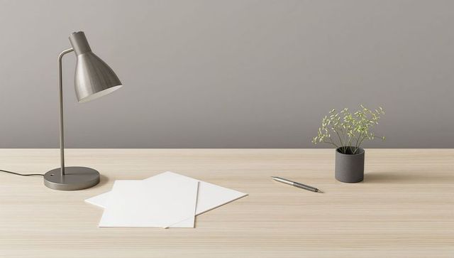 Minimalist neutral calm desk workspace with metal lamp, papers, pen and small potted plant