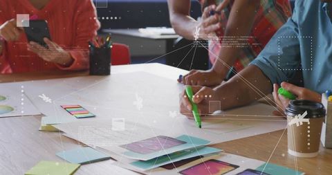 Design team sketching mobile app prototypes with markers, sticky notes and smartphone