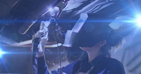 Female Welder Welding Undercarriage with Torch Wearing Helmet Gloves Coveralls in Workshop