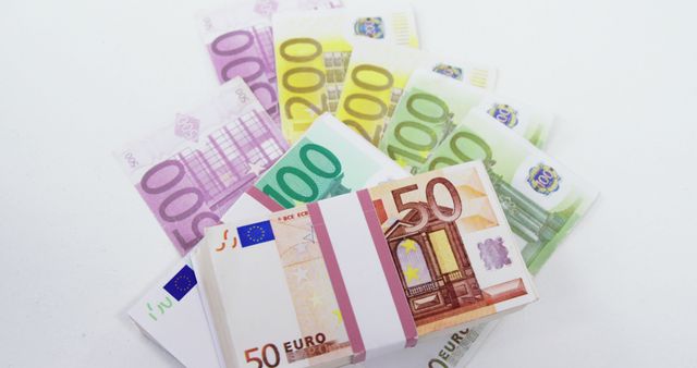 Various denominations of euro banknotes are fanned out on a white background, showcasing the currency used across many European countries. Euro notes are easily recognizable by their distinct colors and sizes, each representing different values.