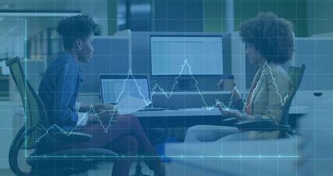 Colleagues engaging in productive office discussion with laptops