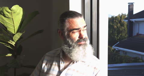 Senior Man with Beard Enjoying Sunlight by Window