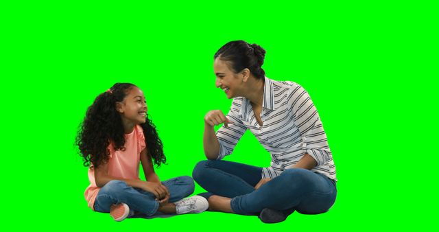 Two people sitting on the floor engaged in a joyful conversation, ideal for family-themed advertisements, educational materials, or promotional content focusing on parenting, family relationships, and childhood experiences. The green screen background allows for easy customization in various projects.