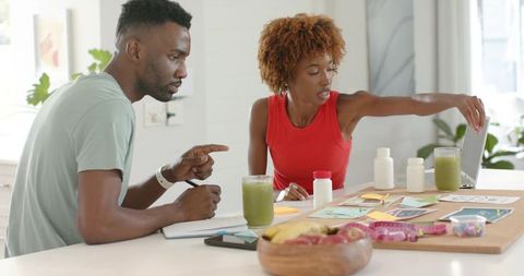 Couple planning healthy nutrition and wellness goals at home with green smoothies and supplements