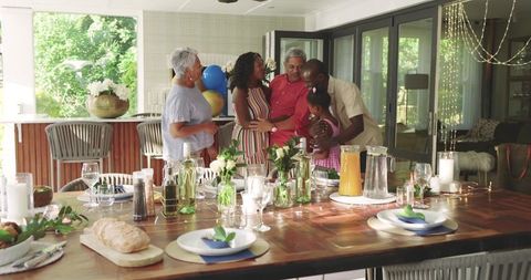 Multigenerational diverse family celebrating together in sunlit kitchen with dining table
