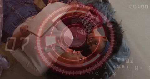 Parent and child bonding on couch using tablet with red futuristic hud overlay and cozy textiles