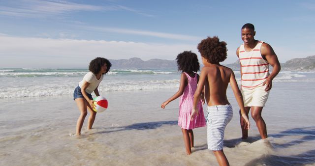 African American family spending quality time at the beach on vacation, playing with a beach ball, and enjoying sunny weather. Perfect for depicting family holidays, coastal activities, and summertime leisure.
