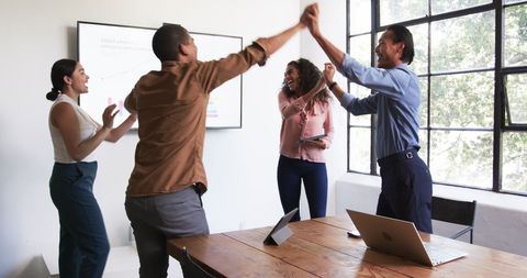 Cheerful Diverse Team Celebrates Success in Modern Office