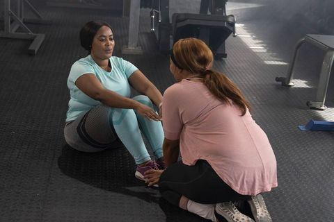 Partners doing sit-ups holding feet for core training and gym motivation with supportive coaching