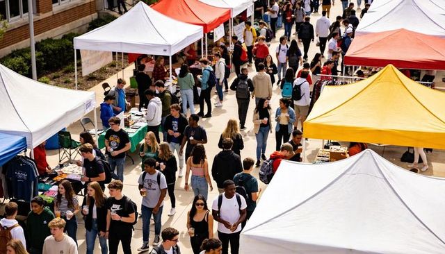 Campus market day with students browsing booths, vendors under white, red, yellow canopies