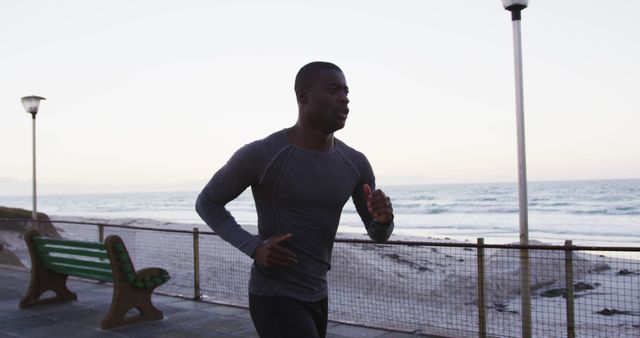 Focused african american man exercising outdoors, running by seaside - Download Free Stock Photos Pikwizard.com