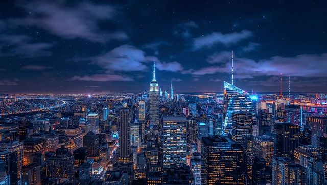 Neon-lit Manhattan skyline from rooftop showcasing spire-topped skyscraper and lit grid