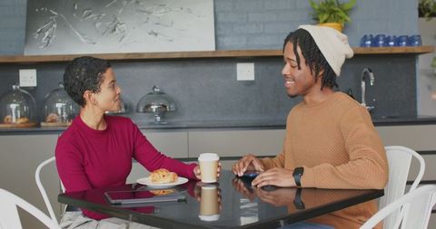 Young couple chatting over coffee and pastry at modern minimalist cafe table, casual urban