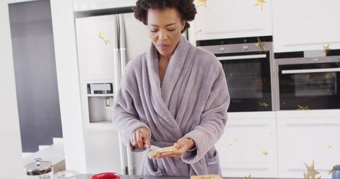 Morning ritual: woman spreading jam on toast in cozy kitchen