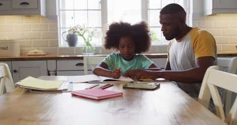 Father Teaching Daughter Homework at Kitchen Table