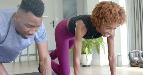Couple doing bodyweight workout at home with kettlebell and natural light, smiling duo