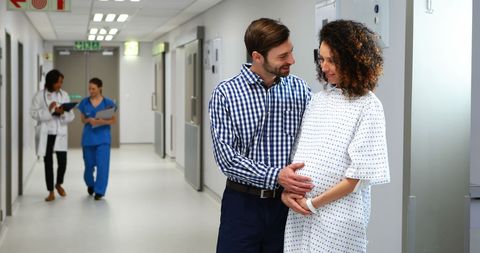 Couple Embracing in Hospital Corridor, Journey of Parent-to-Be