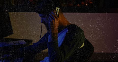 Music producer adjusting headphones in neon studio with midi keyboard and vintage grain