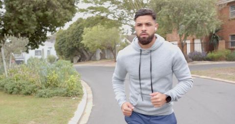 Male Jogger Running Down Suburban Street in Casual Sportswear