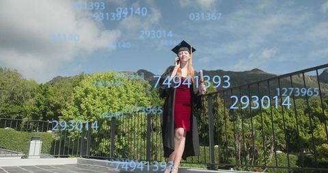 Graduate standing on terrace in graduation cap and gown talking on phone with numeric overlay