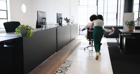 Co-workers enjoying office fun with chair ride adventure